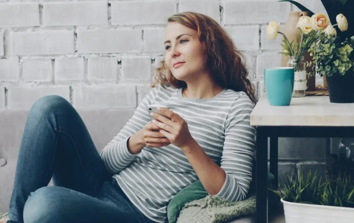 A woman enjoys a relaxing moment on a couch with plants nearby, exuding calm.