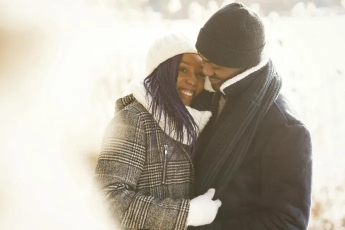 Joyful couple embracing outdoors in winter attire, exuding warmth and love.