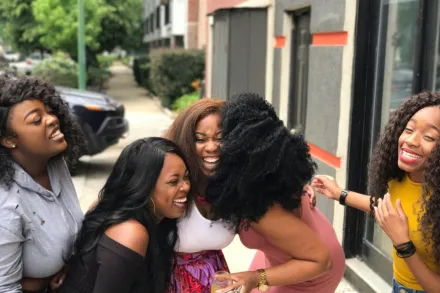 A joyful group of friends sharing a moment of laughter on a sunny day outdoors.