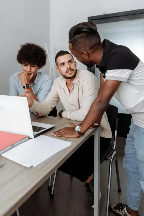 Three men engaged in a collaborative business meeting indoors, discussing ideas.
