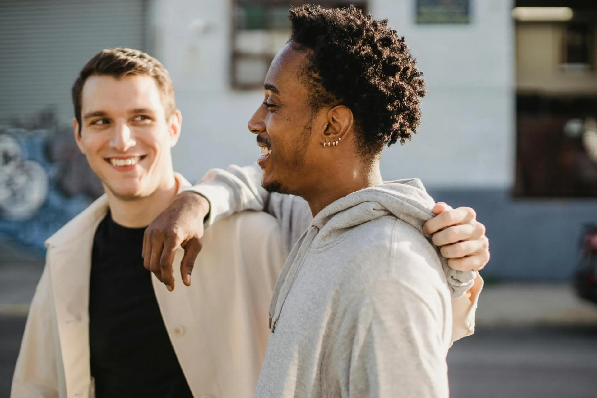 Two friends share a joyful embrace on a sunny street, exuding positivity and friendship.