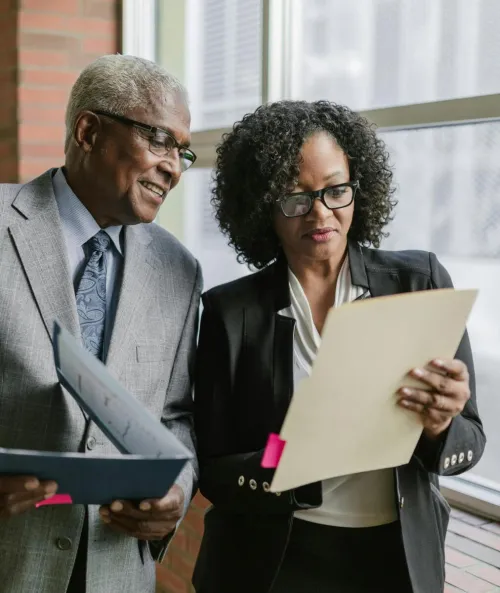 Two business professionals reviewing documents in a corporate office setting.