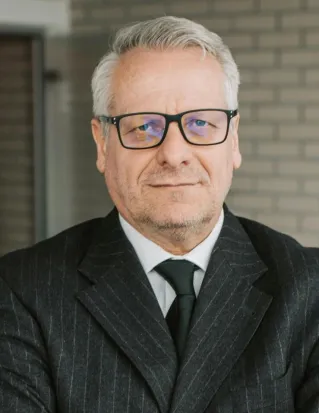 Senior businessman standing confidently with colleagues in a modern office setting.