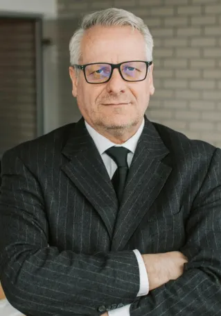 Senior businessman standing confidently with colleagues in a modern office setting.
