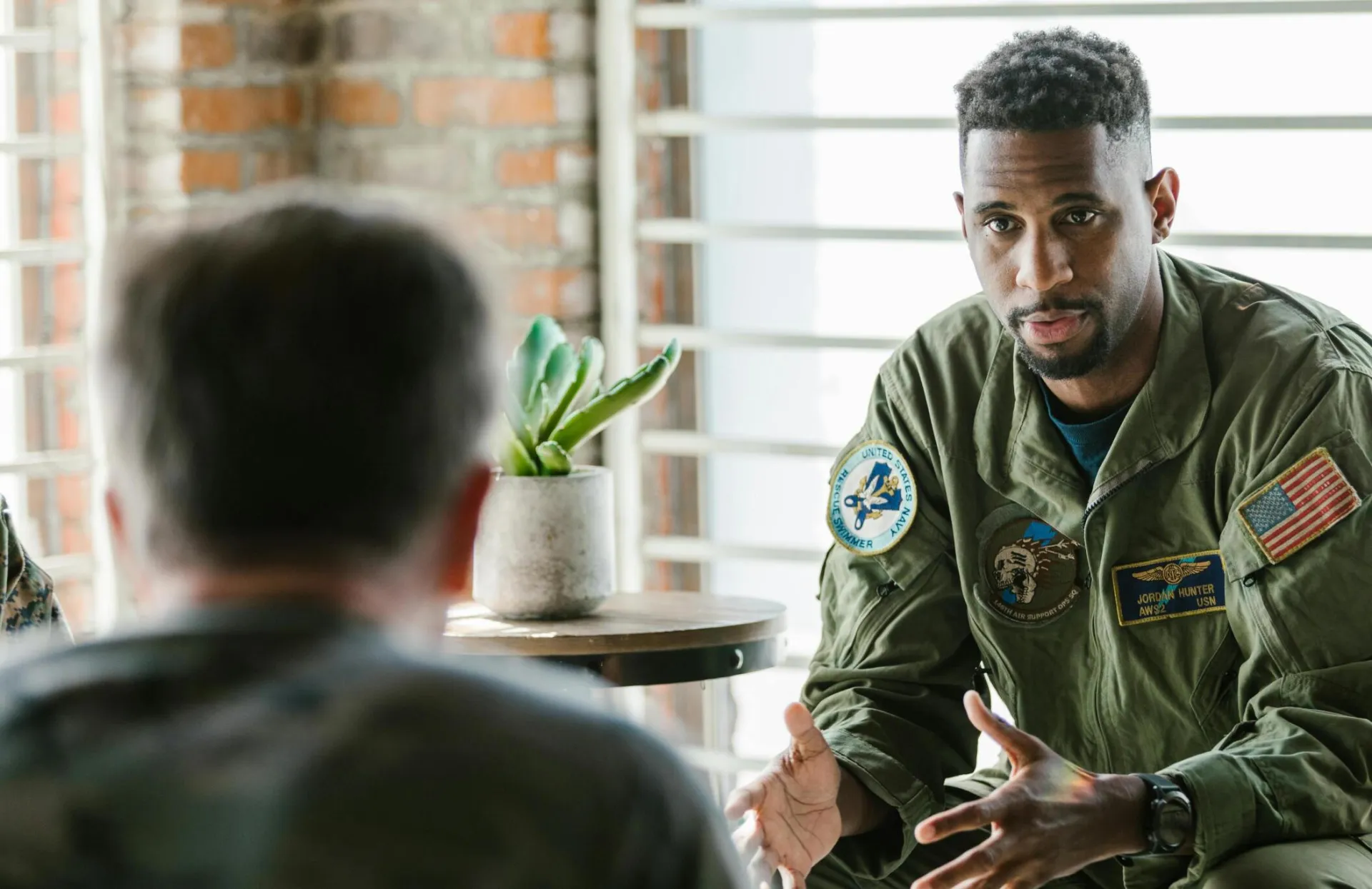 A group of military veterans participate in a supportive therapy session indoors.