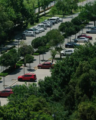 Aerial view showcasing a parking lot surrounded by lush trees and parked cars.