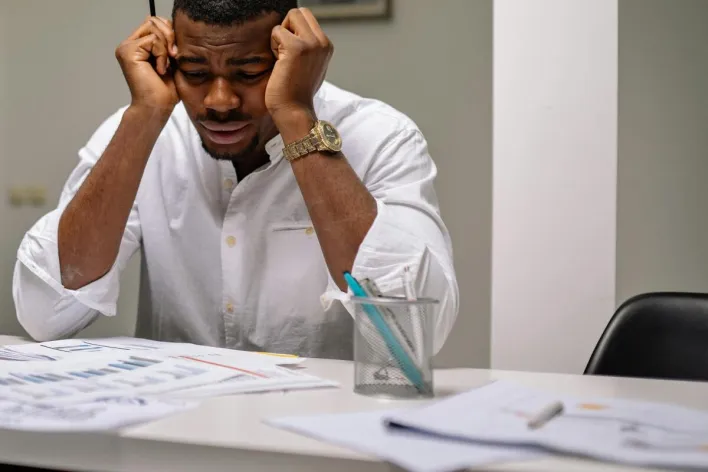 A worried businessman in corporate attire handling stress at his workspace.