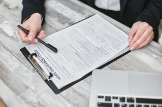 Close-up of hands reviewing a home insurance policy, emphasizing professionalism and finance.