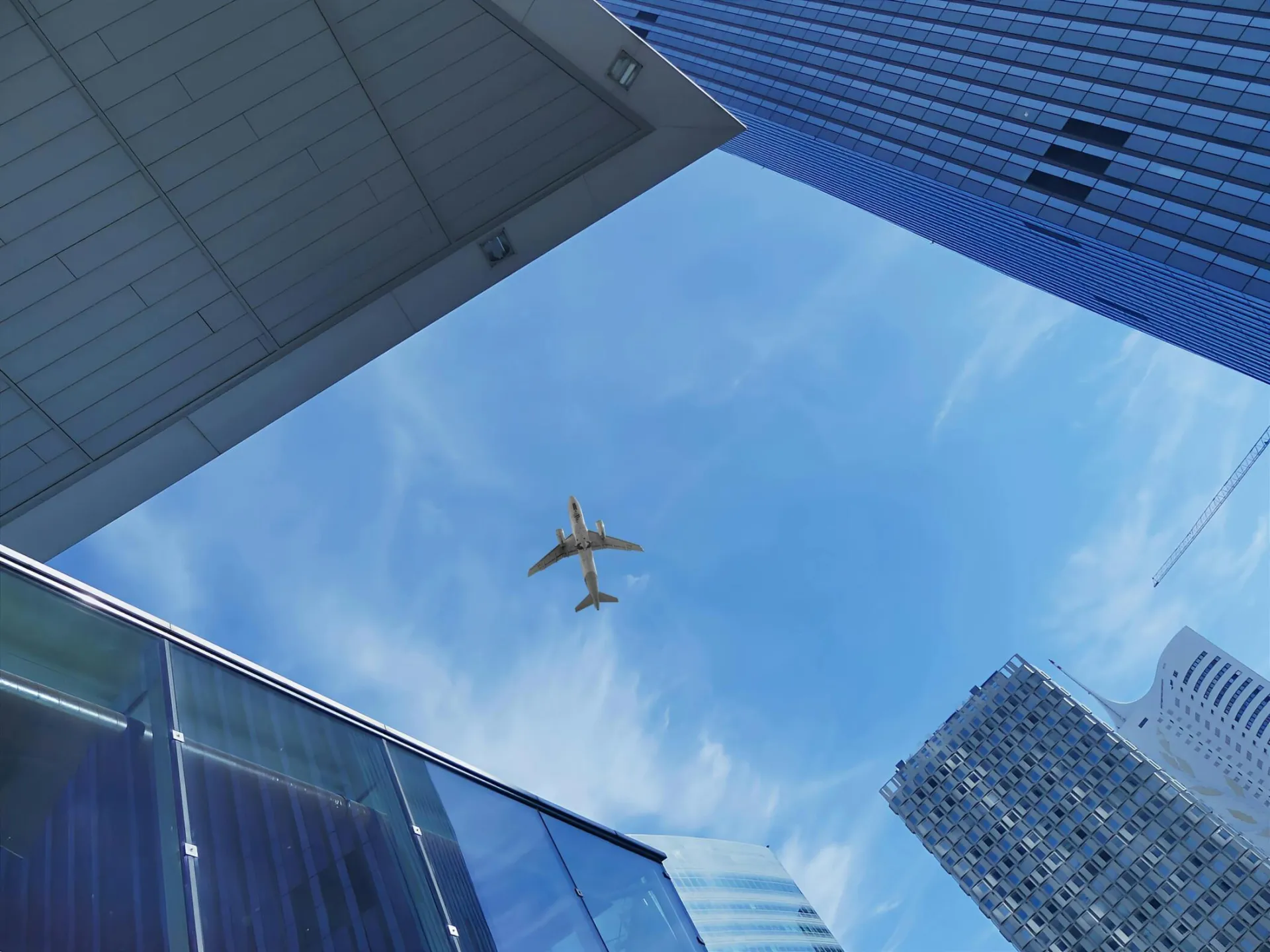 Low angle view of an airplane flying over modern skyscrapers against a blue sky in Vienna.