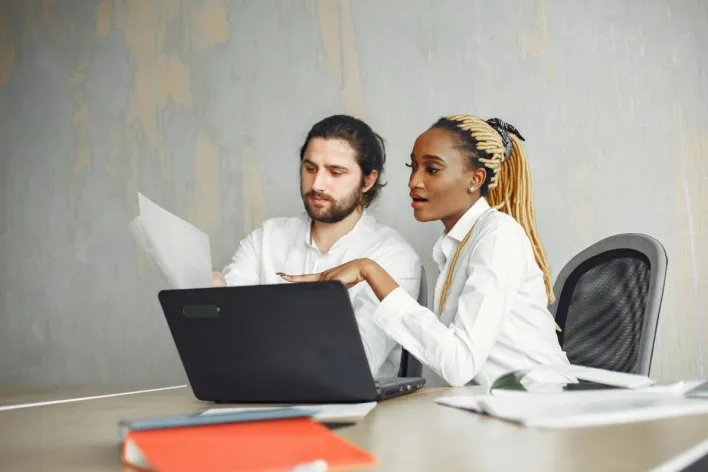 Two professionals in a modern office setting collaborating on a project.