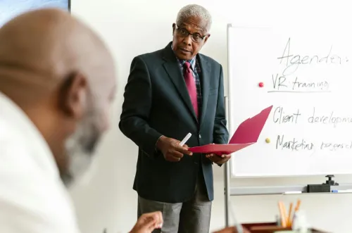 Senior businessman presenting in an office meeting with colleagues.