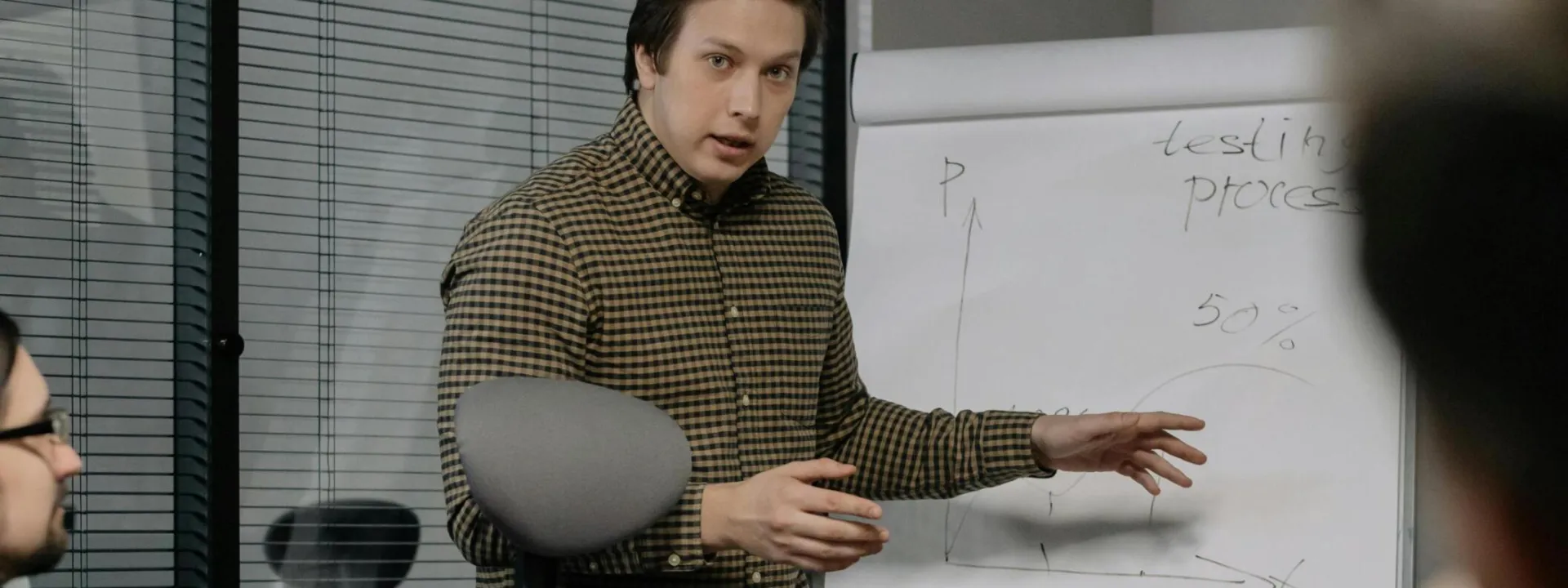 Businessman giving a presentation to colleagues in modern office setting, emphasizing teamwork and communication.
