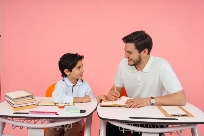 Teacher and young student engaged in study session at school desk.