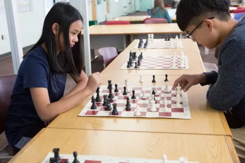 Two teenagers focused on a strategic chess game indoors at school.