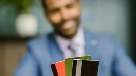 Professional man in suit holding multiple credit cards, emphasizing finance and business concept.