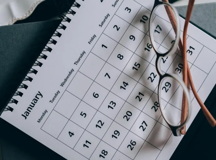 A close-up of a January calendar with eyeglasses on a table, emphasizing planning and organization.