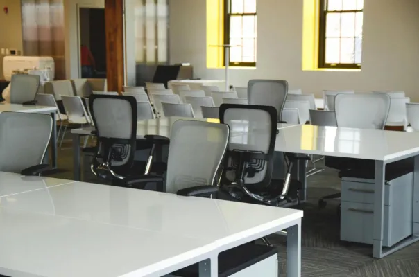 Spacious open office workspace with desks, chairs, and natural lighting.