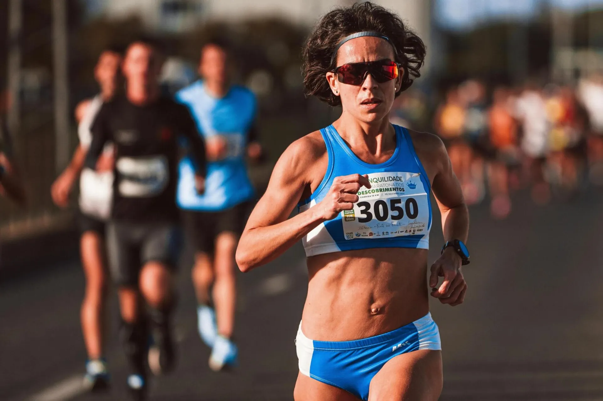 Focused female runner in blue sportswear during a marathon event outdoors.
