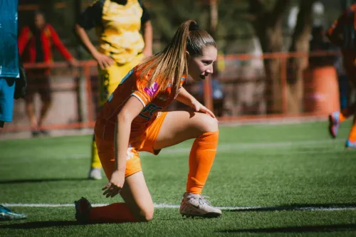 A female football player in action during a match on a sunny day in Chile.