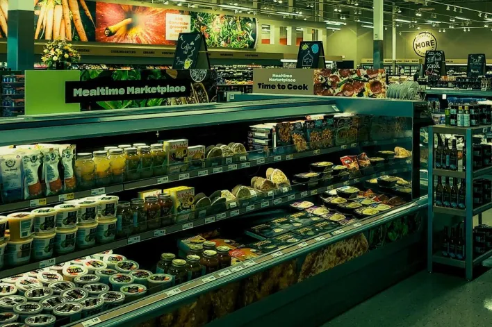 Colorful grocery store aisle with a variety of products on display under bright lighting.