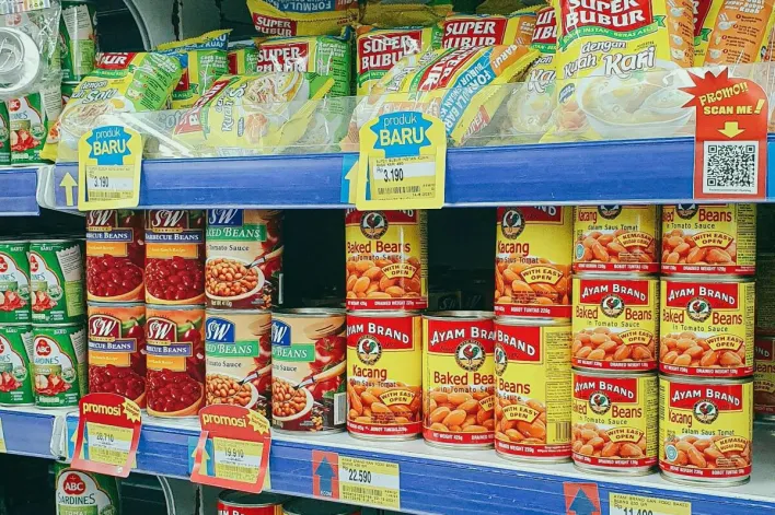 Canned and packaged goods neatly arranged on grocery store shelves, showcasing diverse food products.