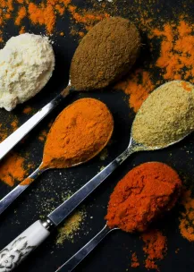 A vibrant array of spices on decorative spoons, showcasing culinary diversity.
