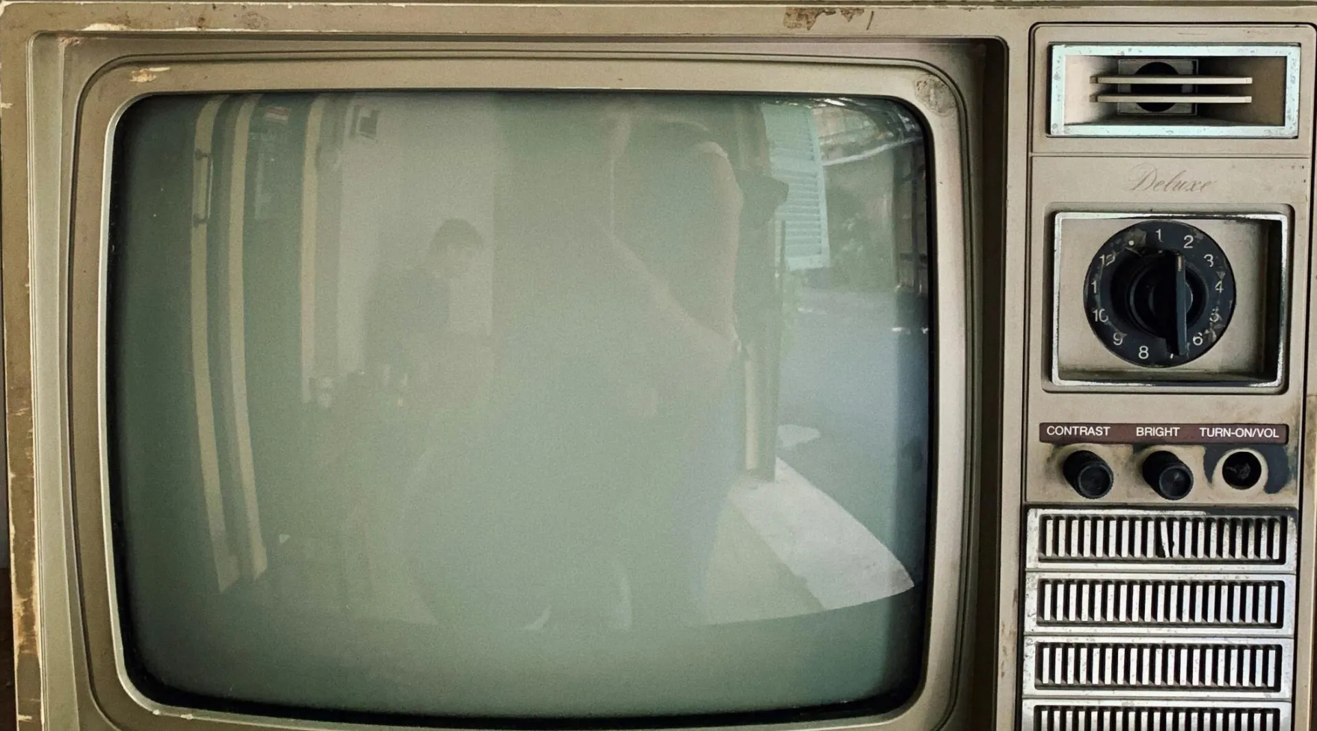 Vintage television set with jars and decor atop, capturing nostalgic charm.