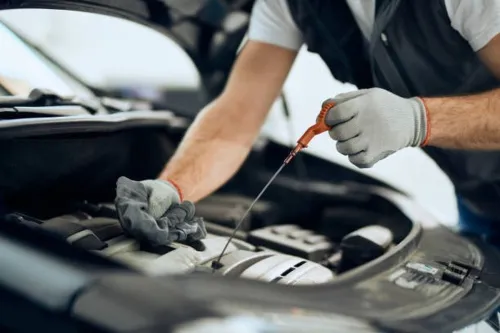 Mechanic in overalls fixing a car engine, focusing on maintenance and repair outdoors.
