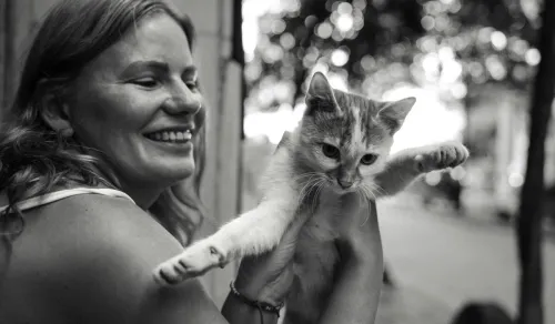 Happy woman holding a playful cat outdoors in Istanbul, capturing a joyful moment.
