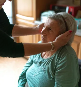 A senior woman receiving attentive home care assistance indoors, promoting comfort and support.