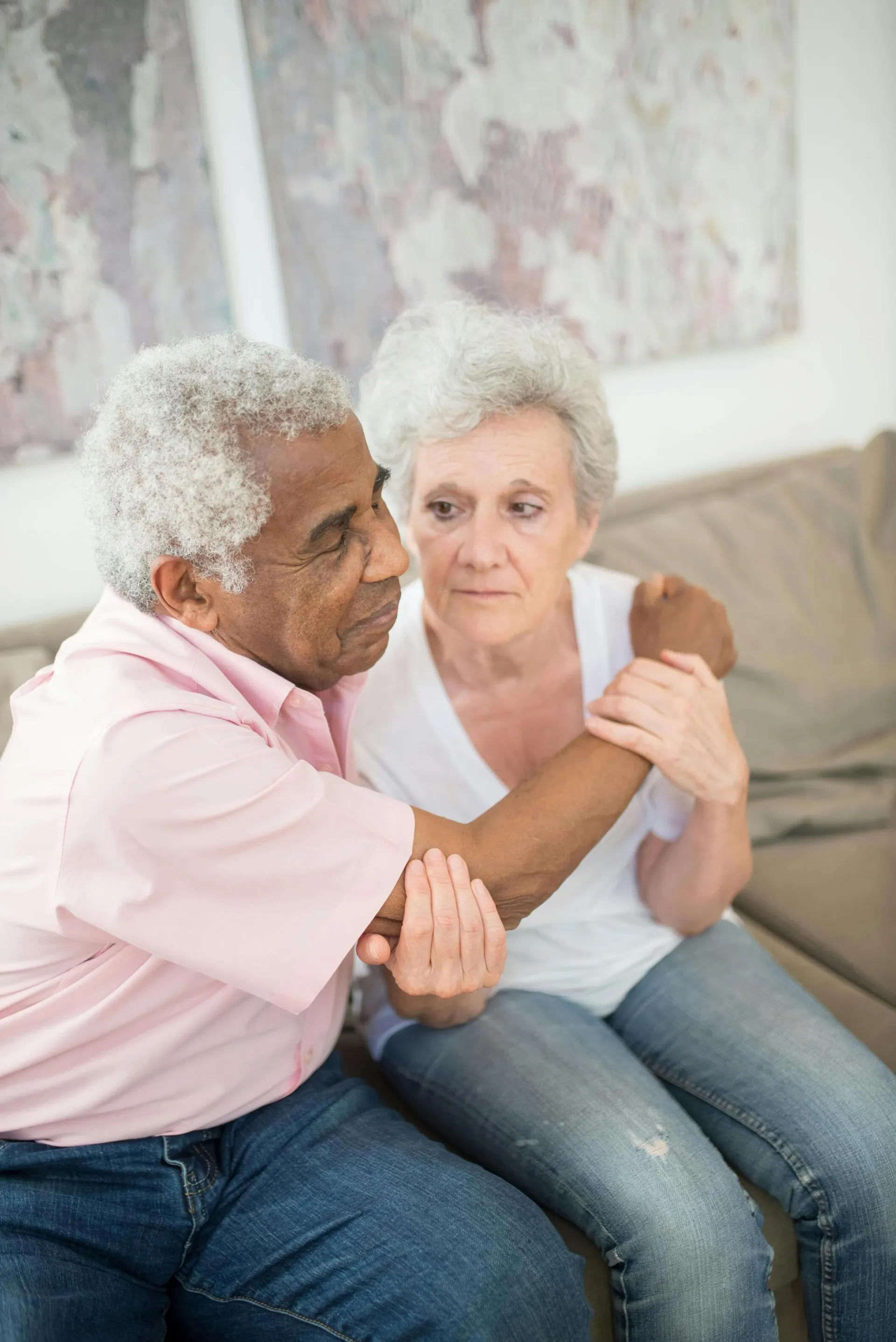 Warm and intimate portrait of an elderly couple sitting closely on a couch, sharing a heartfelt embrace.