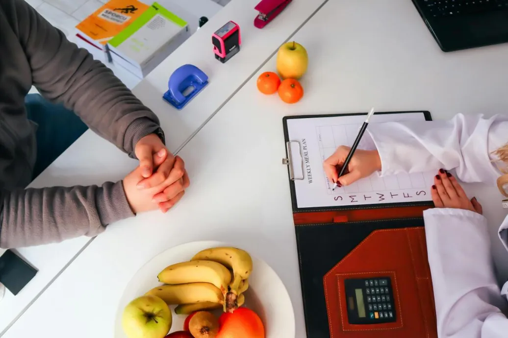 Top view of a dietitian planning a healthy diet with fresh fruits on the table, focusing on health and nutrition.