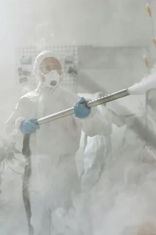 A person in full protective gear fumigating a room to ensure sterilization against viruses.