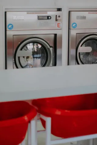 Contemporary laundromat interior with advanced washing machines and red laundry baskets.