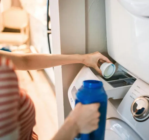 Close-up of a person pouring detergent into a front-loading washer, emphasizing household chores.