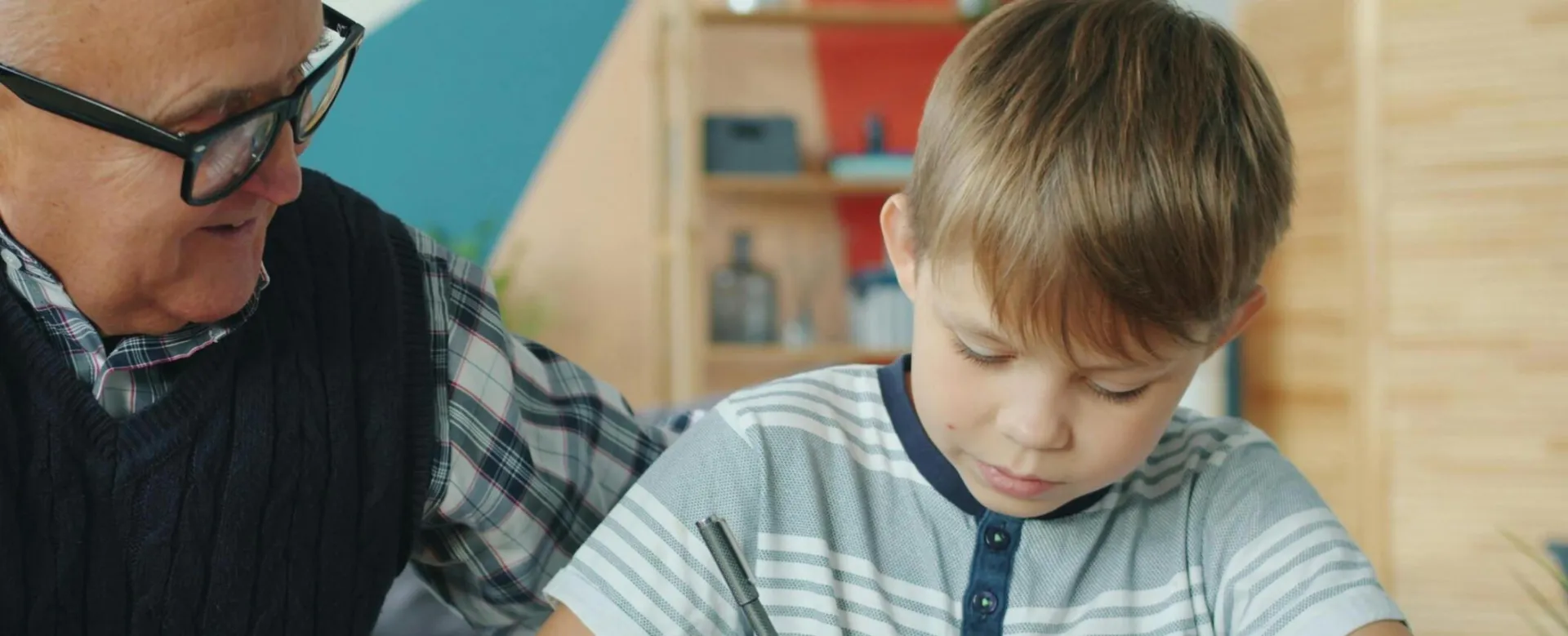 Elderly man assisting young boy with school work at home.