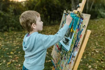 A young boy engages in outdoor painting, capturing creativity and childhood art in nature.
