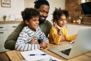 A cheerful family of three with a child hugging on a sofa indoors.