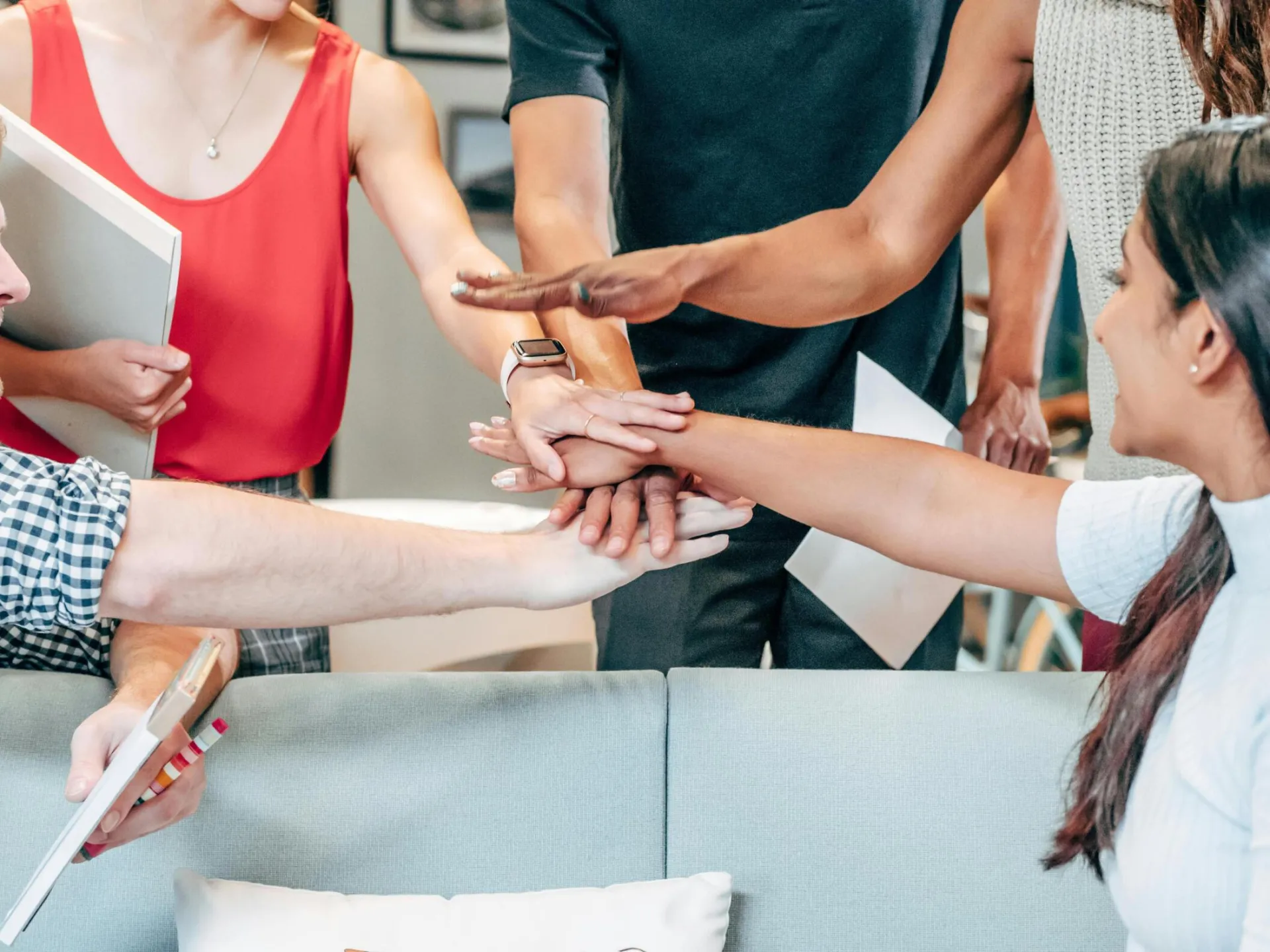 A diverse group of coworkers uniting hands in an office setting, symbolizing teamwork and collaboration.