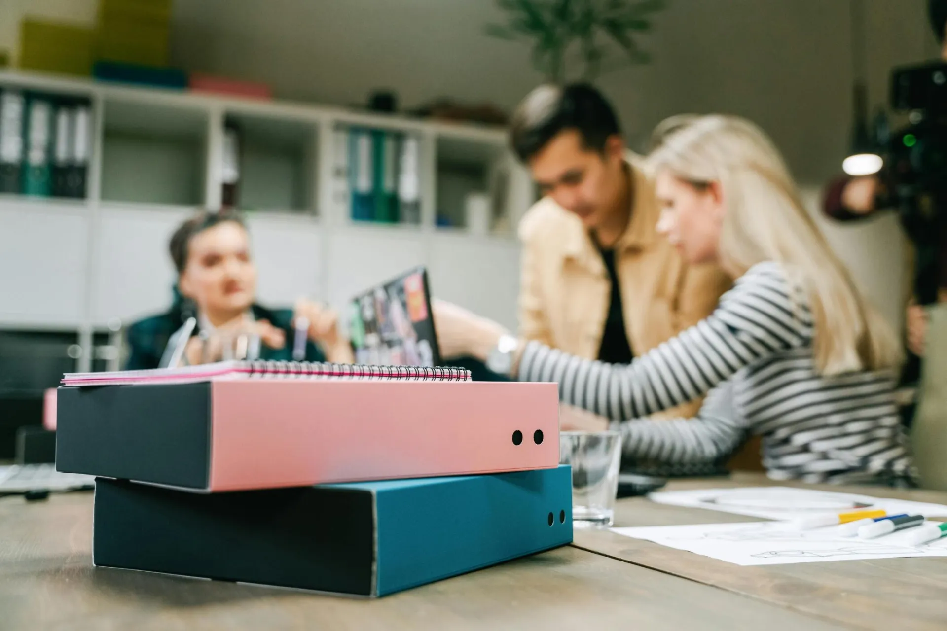 Focused group discussing strategy in an office with binders and modern decor.