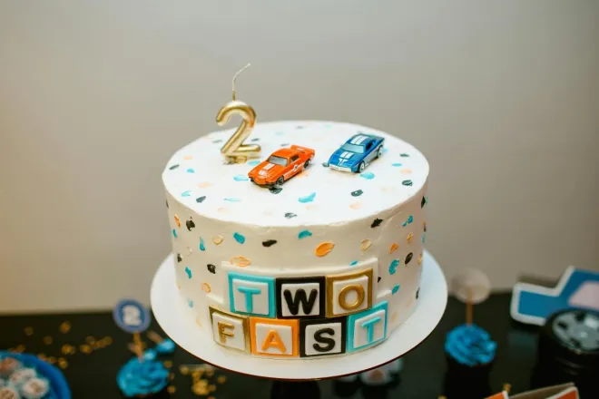 A vibrant car-themed birthday cake with toy cars and playful decorations, perfect for celebrations.