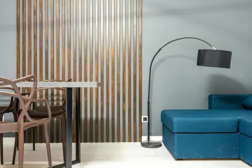Contemporary living room interior with couch against lamp and table with armchairs on wooden floor at home