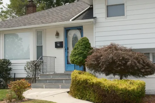Inviting suburban home with a distinctive blue front door and well-kept shrubs.