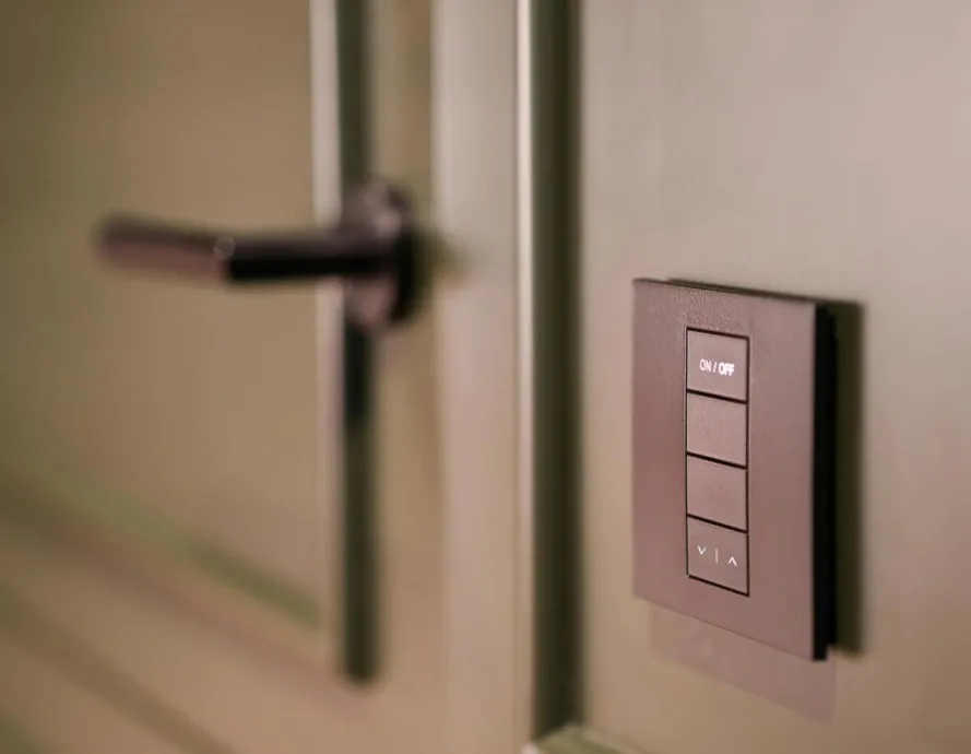 A smart light switch on a wall next to a modern door handle, emphasizing home automation.