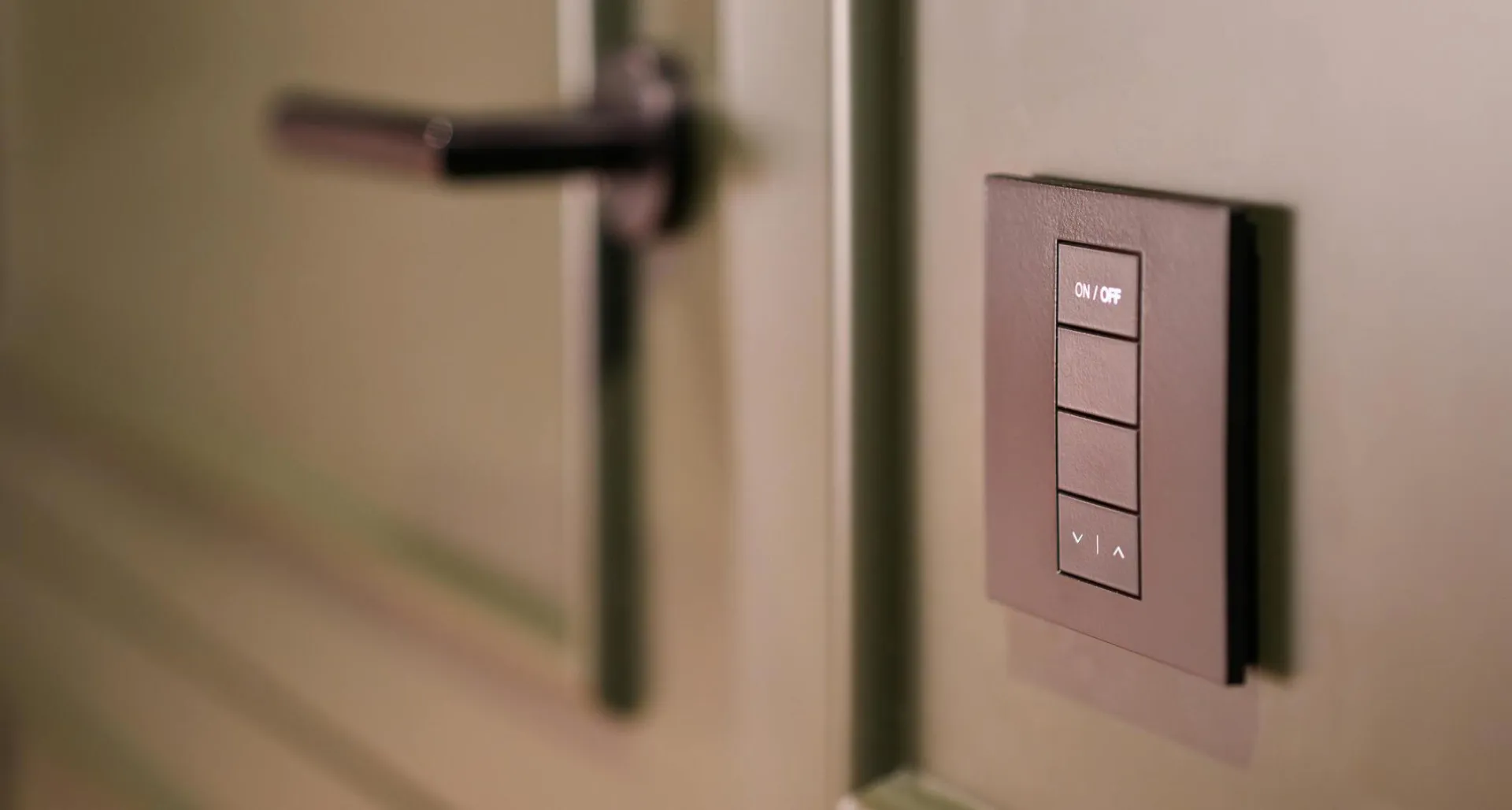 A smart light switch on a wall next to a modern door handle, emphasizing home automation.