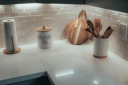 Minimalist kitchen corner with cutting boards, utensils, and dishwasher pods.