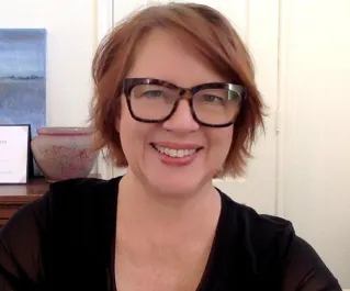 Confident woman in glasses smiling at a cafe in Saint Petersburg, perfect for lifestyle or business themes.