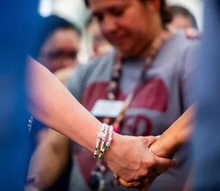 A diverse group of individuals holding hands in a supportive and united gesture, conveying unity.