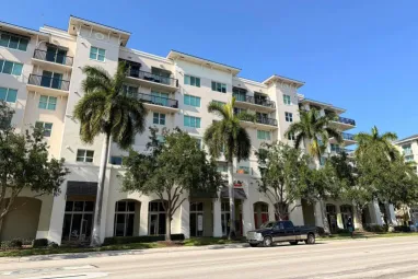 A modern apartment building with palm trees on a clear sunny day.