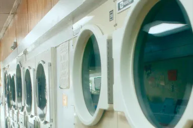 Interior view of a clean and organized laundromat with multiple washing machines lined up.